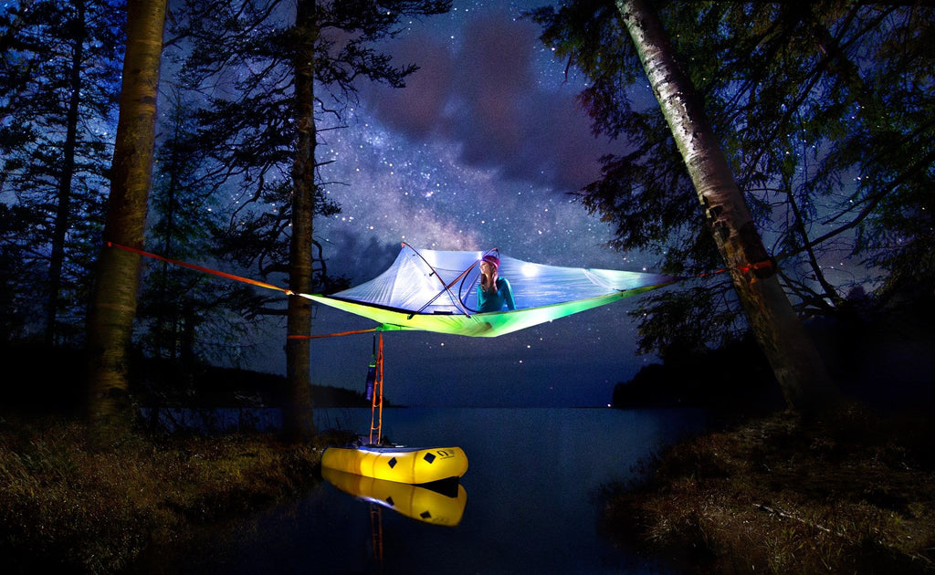 woman in tree tent at night with dingy boat