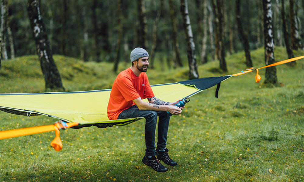 man smiling sat in camping hammock (4553640378441)