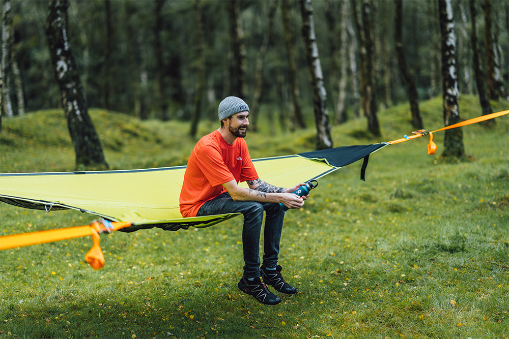 man smiling sat in camping hammock (4553640378441)