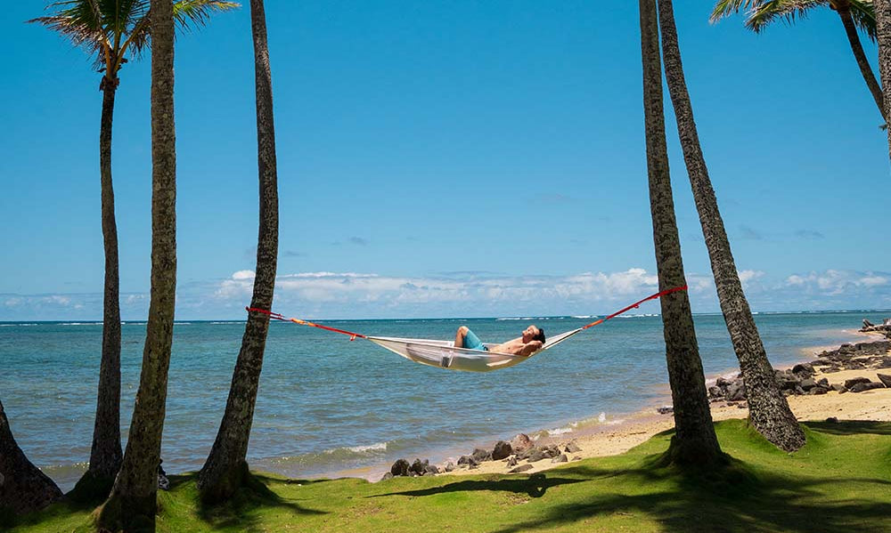 Man laid in ocean hammock on beach (6649462653001)